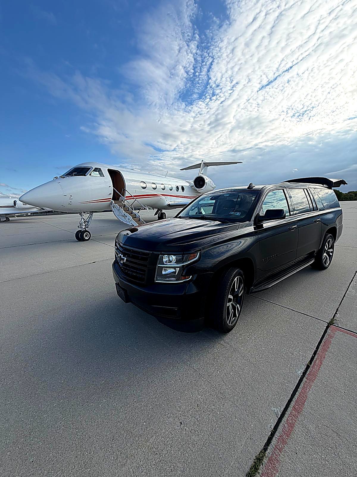 Black Suburban beside a private jet at Philadelphia International Airport