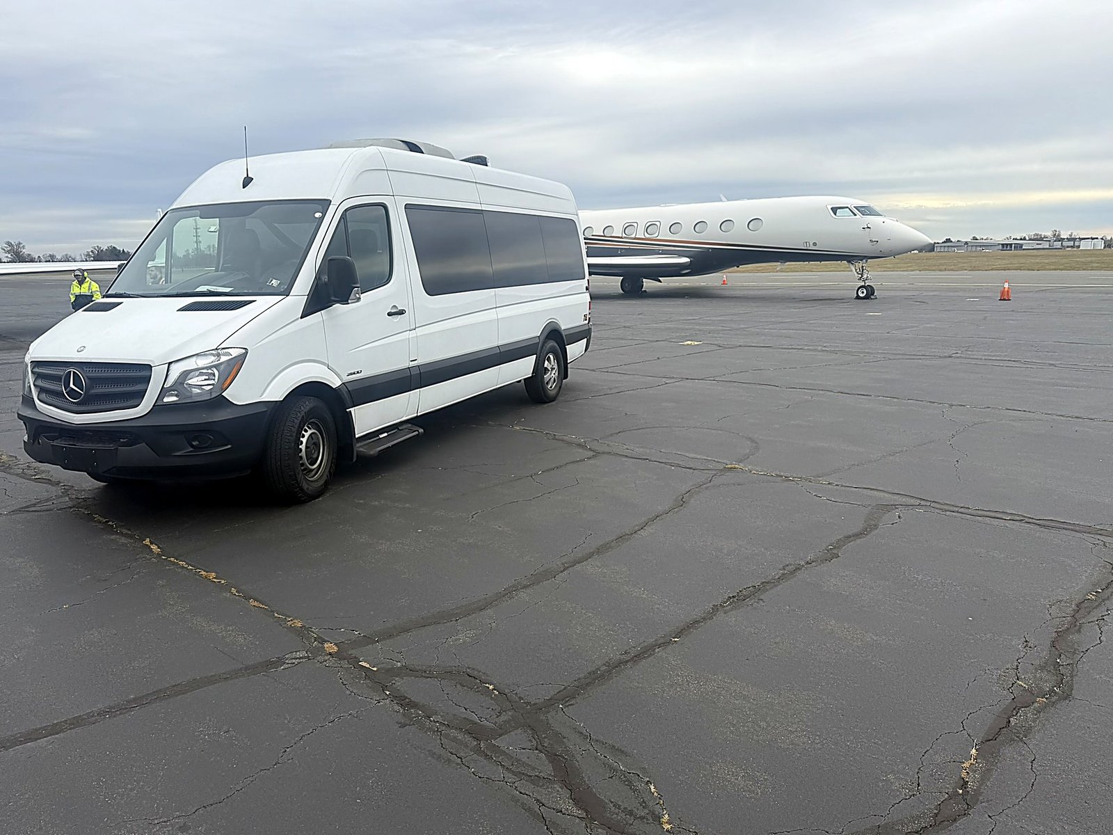 White Sprinter van with private jets on tarmac
