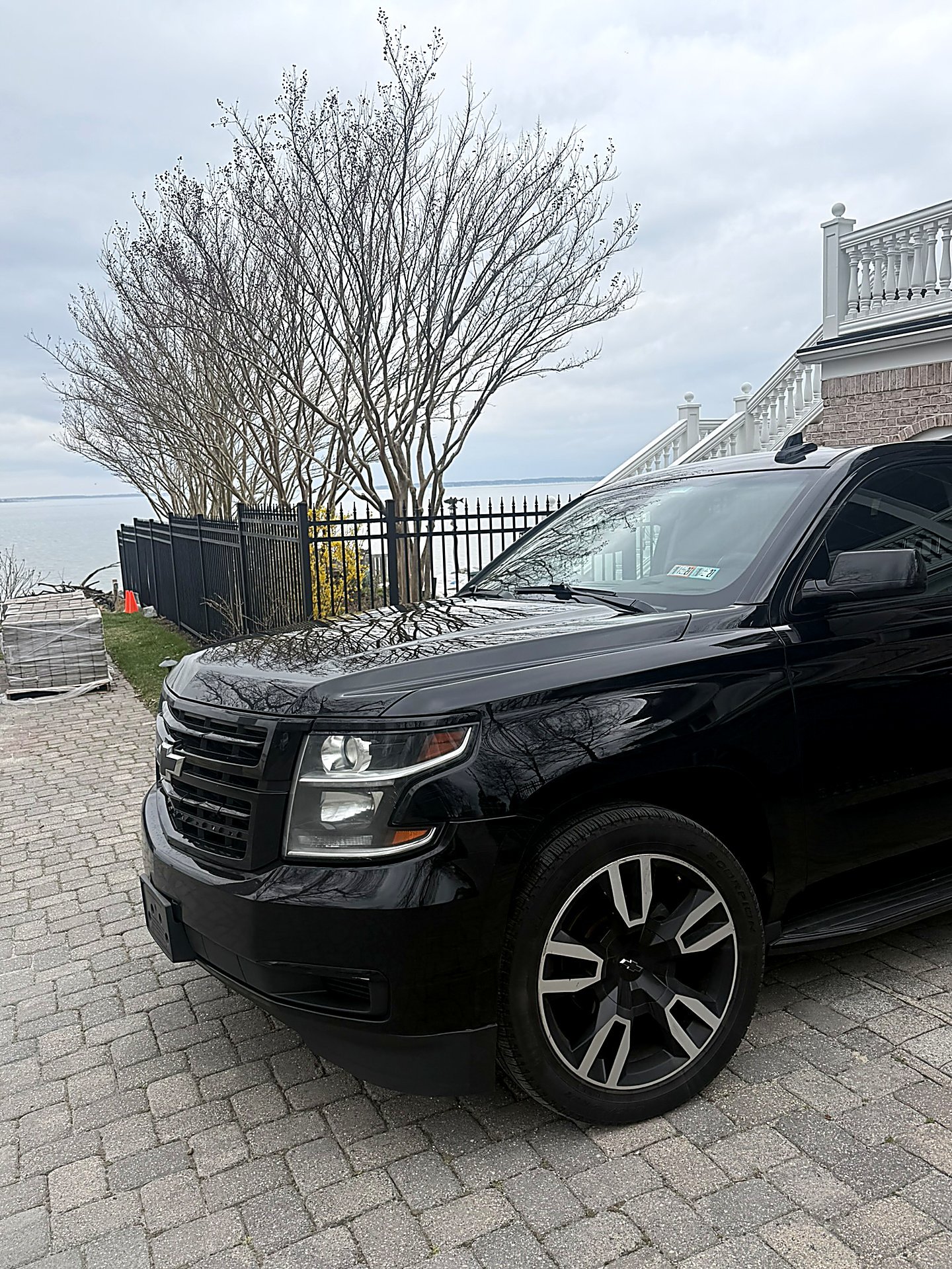 Black SUV parked on a brick driveway near the waterfront