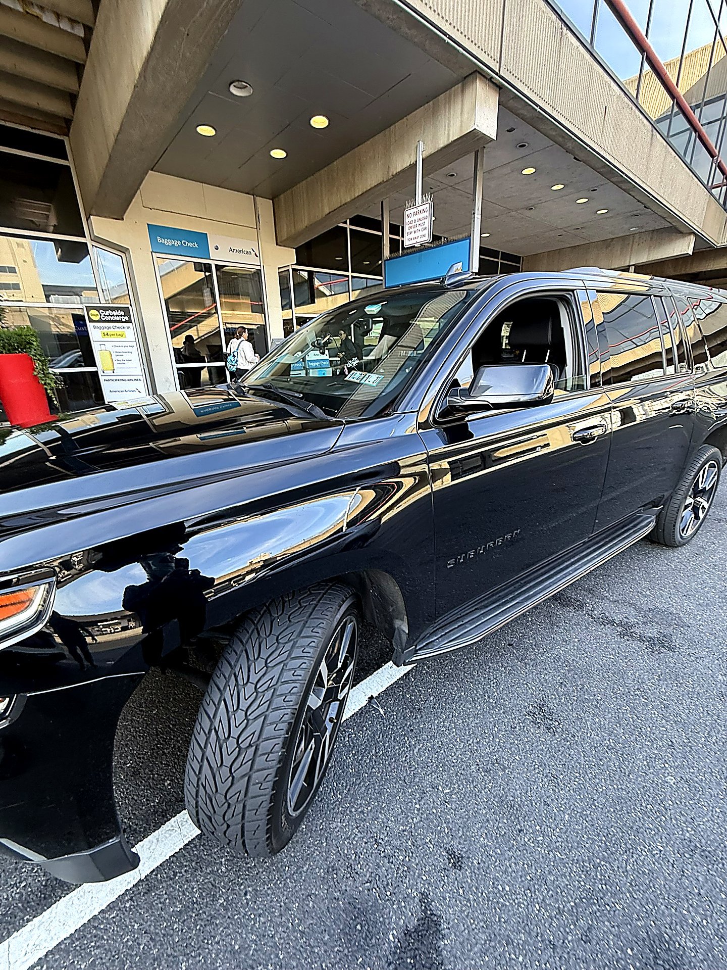 Black SUV at an airport terminal entrance during the day