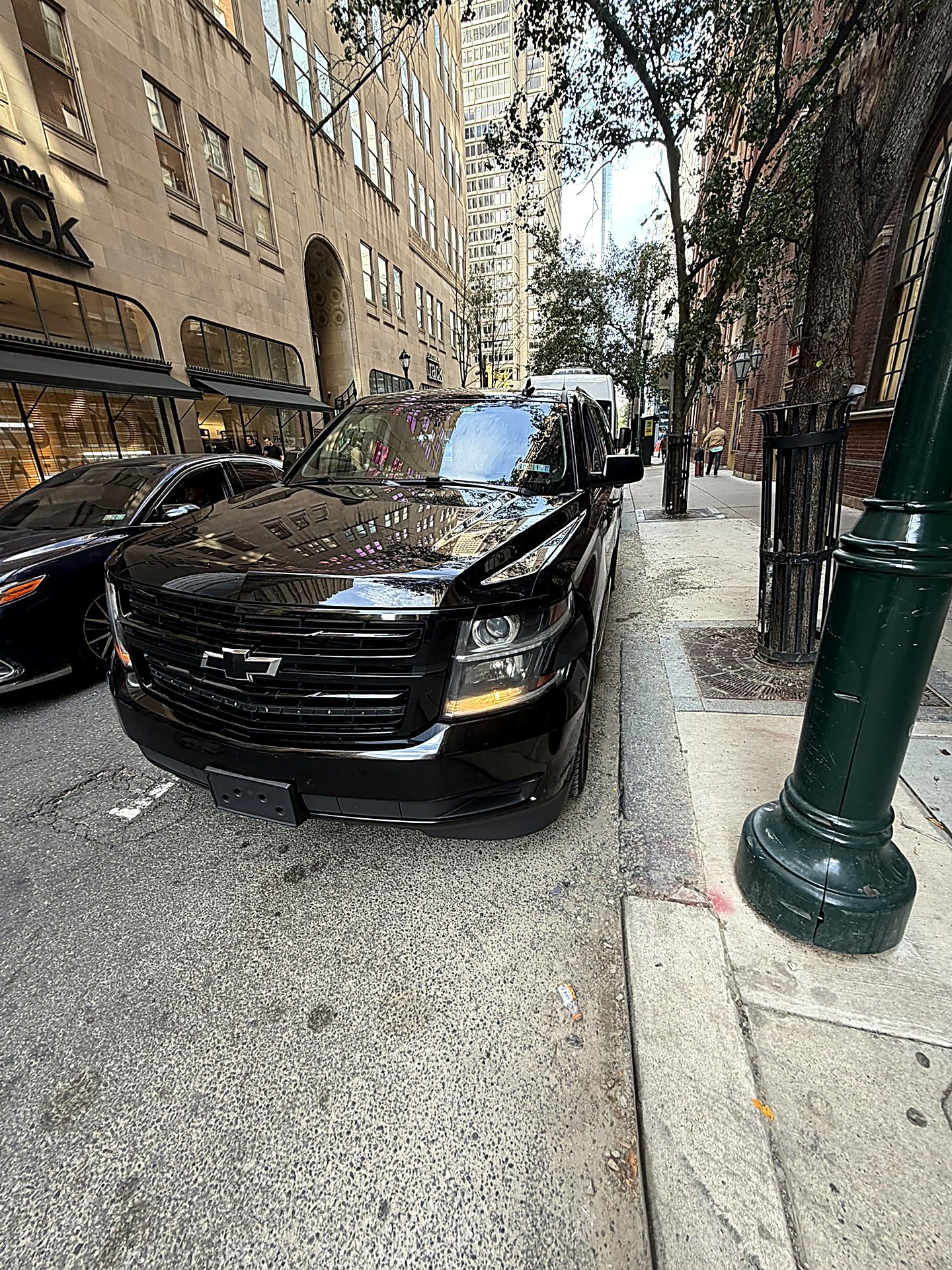 Black SUV parked on a city street in front of a stone building