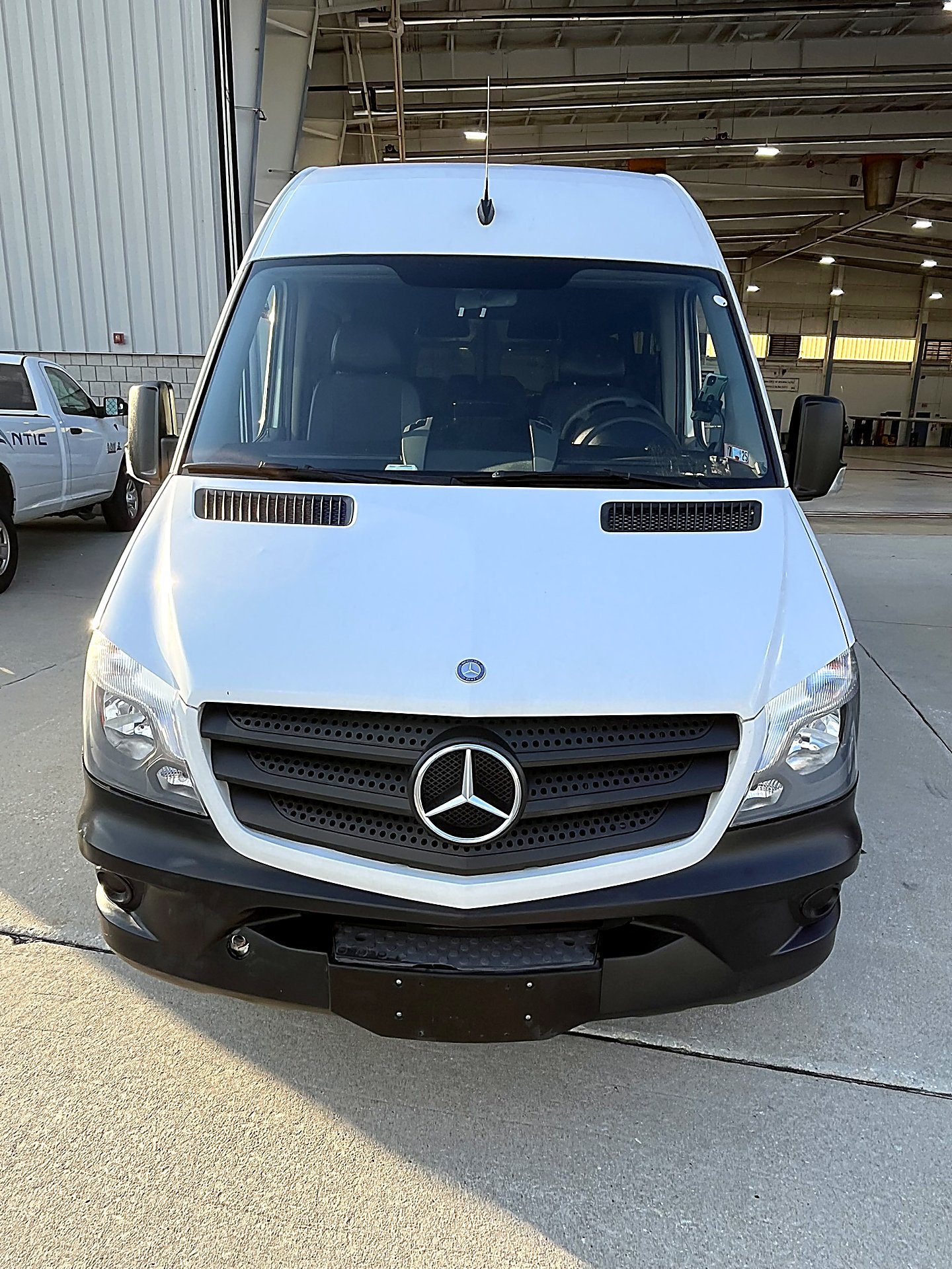 White Mercedes-Benz Sprinter van front view outside a warehouse