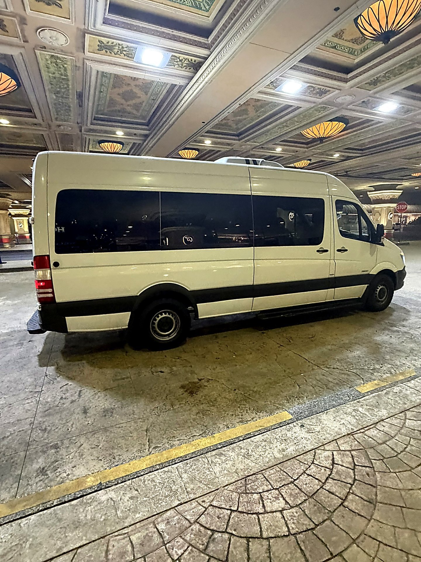 White Sprinter van parked under a covered hotel entrance at night