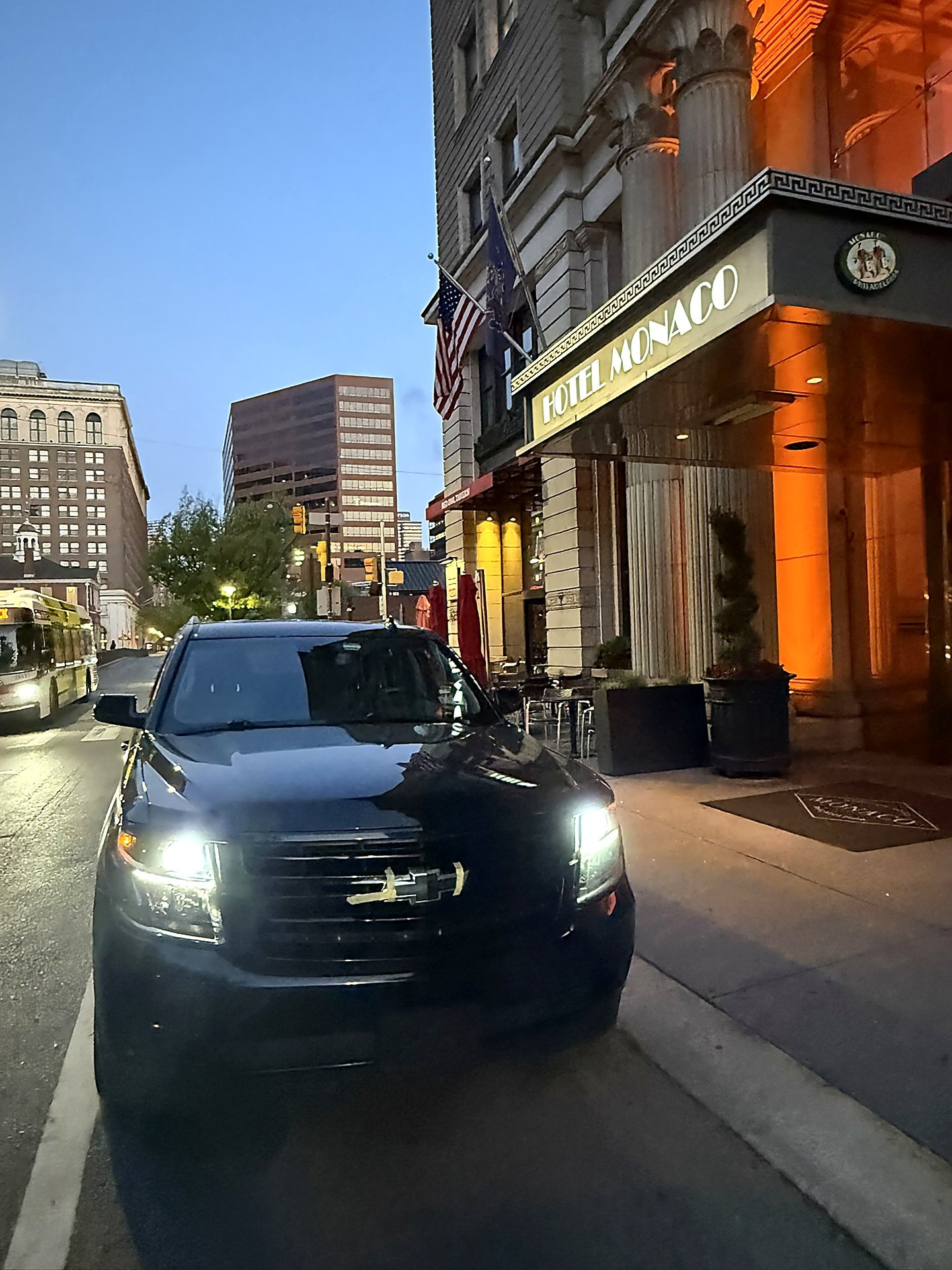 Black SUV with headlights on in front of the Hotel Monaco entrance