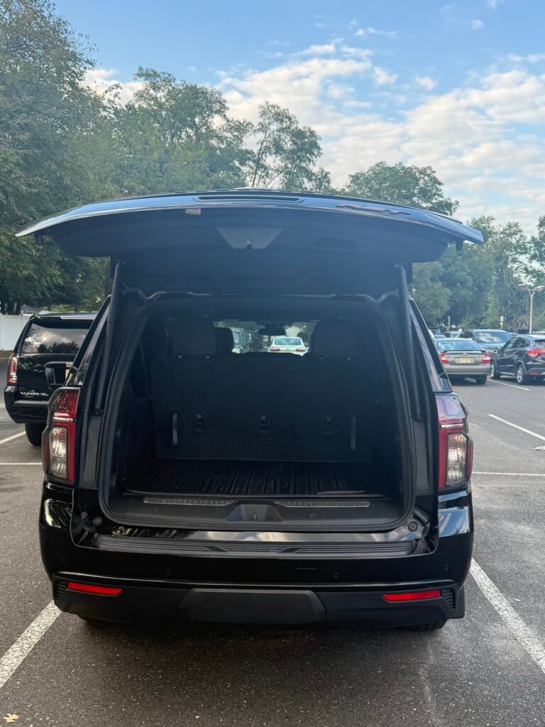 Chevrolet Suburban rear cargo area with the hatch open for airport luggage transportation.